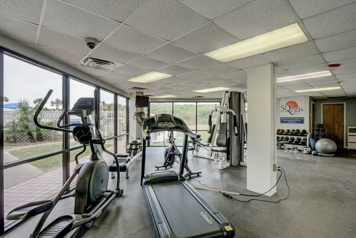 A bright, modern fitness center fully equipped with treadmills, ellipticals, and weightlifting stations. The room is spacious and clean, encouraging an active lifestyle.