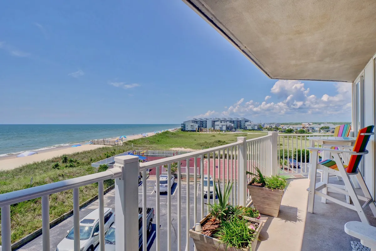 A tranquil balcony scene overlooks the expansive sandy beach and sparkling Atlantic Ocean. Comfortable seating and potted plants create a relaxing retreat to enjoy sunrises, sunsets, and panoramic views of the coast, while the beach and gentle surf beckon just steps away.