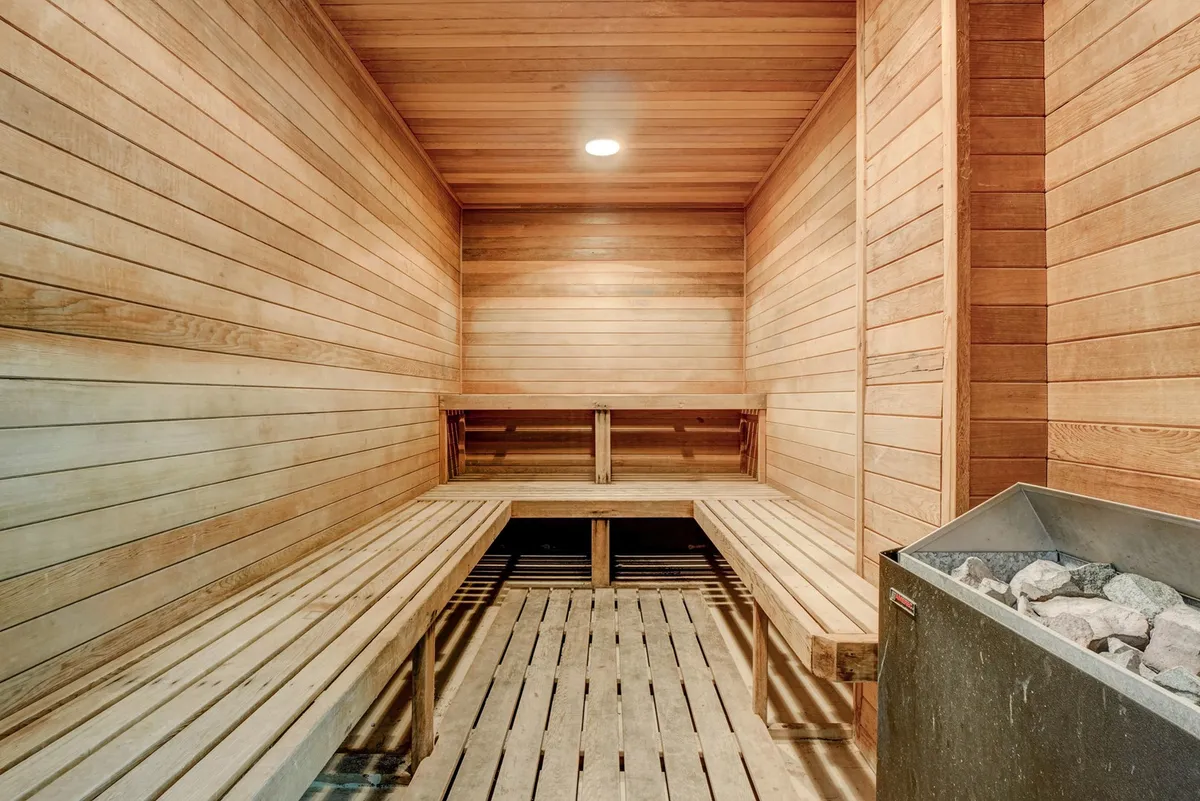 A serene sauna with wooden benches and a central stone heater, inviting guests for moments of relaxation and mindful reflection.