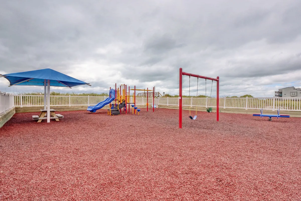 A vibrant playground scene with swings and colorful equipment, adjacent to a picnic area. The joyful mood captures families and children at play, with space for picnicking and socializing nearby.